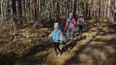 女人在大自然中行走北欧。 女孩和孩子使用跋涉棒和北欧杆，背包。 家庭旅行